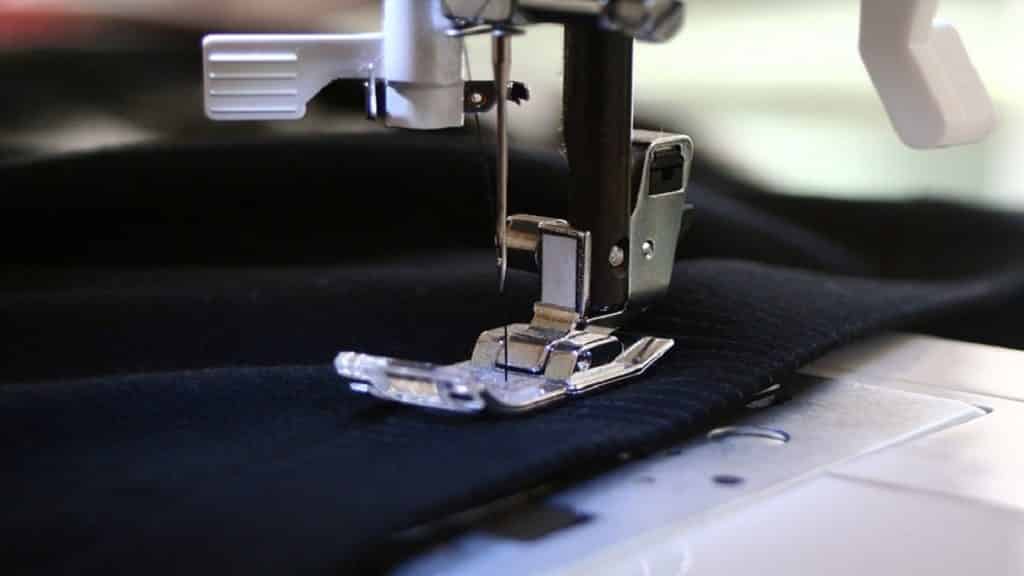 A sewing machine is being used to stitch a black fabric